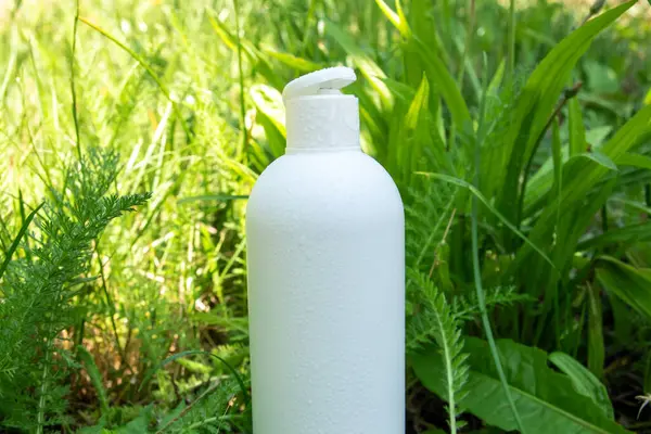 Yeşil çimlerde krema, merhem ya da yağ için beyaz plastik şişe. Kozmetik için doğa arkaplanı. 