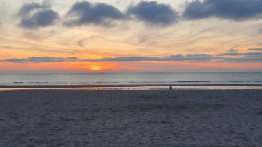 Gün batımlı güzel sahil. Suya yakın kumda yürüyorum. Denizin üzerinde çok bulut.