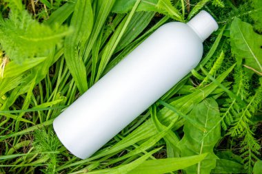 Yeşil çimlerde krema, merhem ya da yağ için beyaz plastik şişe. Kozmetik için doğa arkaplanı. 