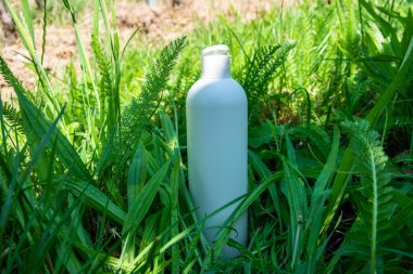Yeşil çimlerde krema, merhem ya da yağ için beyaz plastik şişe. Kozmetik için doğa arkaplanı. 