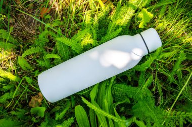 Suyu yeşil çimlerin üzerinde beyaz termo paslanmaz şişede tazeliyorum..