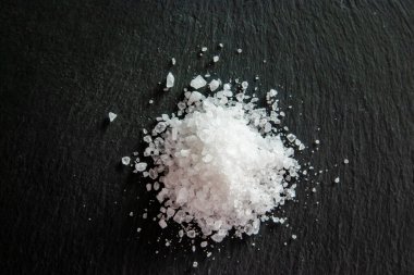 Siyah arka planda beyaz tuz kristalleri var. Yemeği pişirmek için tuz kristalleri. Restoran için menü.