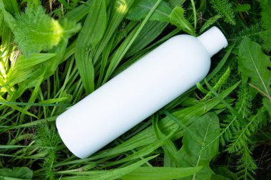 Yeşil çimlerde krema, merhem ya da yağ için beyaz plastik şişe. Kozmetik için doğa arkaplanı. 