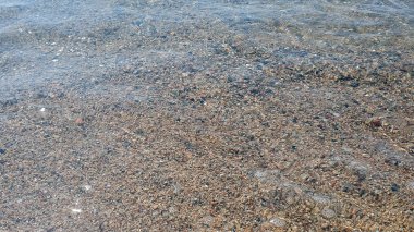 Deniz taşları. Güneşli bir günde şeffaf su ve dalgalar çok taşlı..