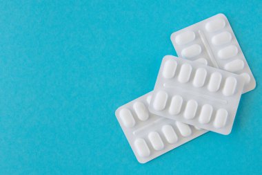 Mavi arka planda beyaz pakette bir sürü ilaç ve ilaç var. Sağlık hizmetleri kavramı.