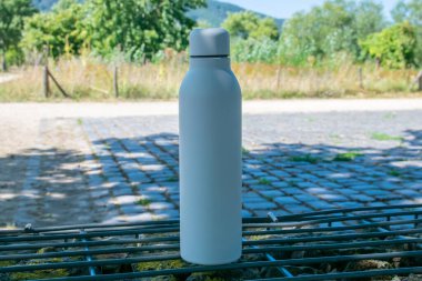 Beyaz termo paslanmaz şişe. Arka planda ferahlatıcı su var..