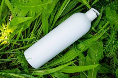 Yeşil çimlerde krema, merhem ya da yağ için beyaz plastik şişe. Kozmetik için doğa arkaplanı. 