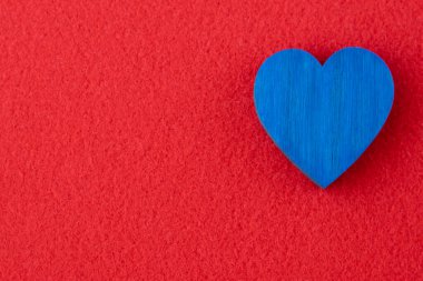 Kırmızı kumaş arka planında mavi ahşap kalp. Metin için yeri olan kart için romantik arkaplan.
