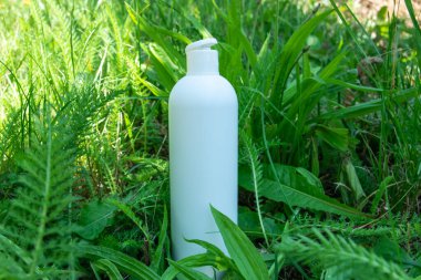 Yeşil çimlerde krema, merhem ya da yağ için beyaz plastik şişe. Kozmetik için doğa arkaplanı. 