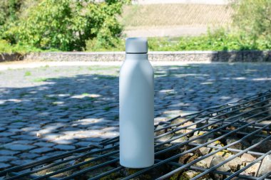 Beyaz termo paslanmaz şişe. Arka planda ferahlatıcı su var..