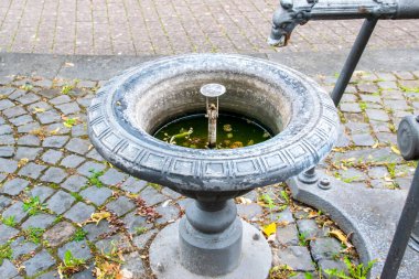 Outdoor old cast fountain without water on the street for city decoration. Autumn holiday. clipart