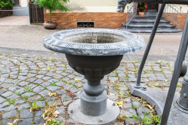 Outdoor old cast fountain without water on the street for city decoration. Autumn holiday. clipart