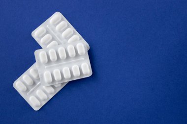 Koyu mavi arka planda beyaz pakette bir sürü ilaç ve ilaç var. Sağlık sigortası konsepti. Metin için boşluk.