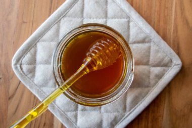 Balpeteği ve sarı kaşıkla bal kavanozu ahşap masada kal..