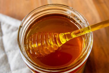 Balpeteği ve sarı kaşıkla bal kavanozu ahşap masada kal..