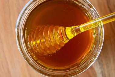 Balpeteği ve sarı kaşıkla bal kavanozu ahşap masada kal..