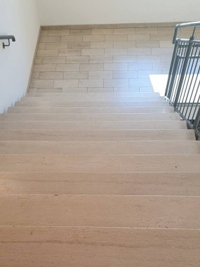 Binanın içinde mermer taştan bej merdivenler ve metal parmaklıklar olan iç merdiven.. 