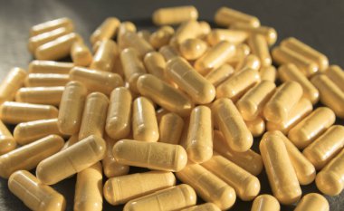 Siyah taş arka planda saydam pakette bir sürü tıbbi sarı hap ve uyuşturucu var. Sağlık sigortası konsepti. BAA ya da biyolojik olarak aktif katkı maddeleri.