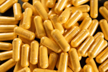 Siyah taş arka planda saydam pakette bir sürü tıbbi sarı hap ve uyuşturucu var. Sağlık sigortası konsepti. BAA ya da biyolojik olarak aktif katkı maddeleri.