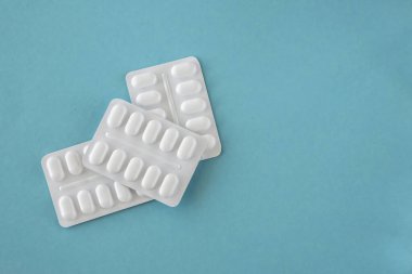 Kağıt mavisi arka planda beyaz pakette ilaç ve ilaç var. Sağlık hizmetleri kavramı.