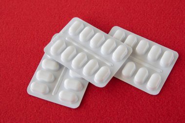 Kırmızı arka planda beyaz pakette bir sürü ilaç ve ilaç var. Sağlık hizmetleri kavramı.