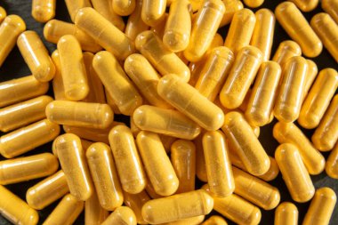 Siyah taşın üzerinde saydam pakette bir sürü tıbbi sarı hap ve uyuşturucu var. Sağlık sigortası konsepti. BAA ya da biyolojik olarak aktif katkı maddeleri.