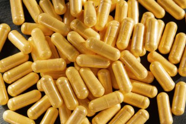 Siyah taş arka planda saydam pakette bir sürü tıbbi sarı hap ve uyuşturucu var. Sağlık sigortası konsepti. BAA ya da biyolojik olarak aktif katkı maddeleri.