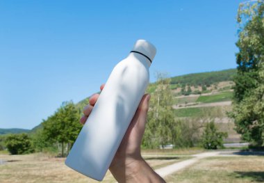 Beyaz termodinamik paslanmaz şişeyle el ele tutuşmak doğada ferahlatıcı su demektir..