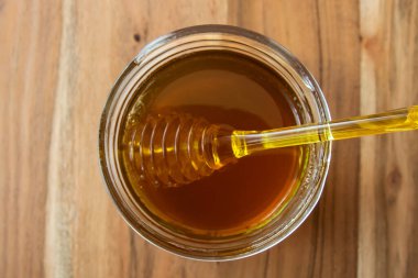 Balpeteği ve sarı kaşıkla bal kavanozu ahşap masada kal..