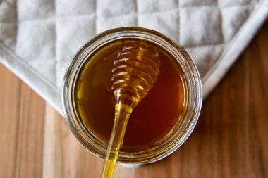 Balpeteği ve sarı kaşıkla bal kavanozu ahşap masada kal..