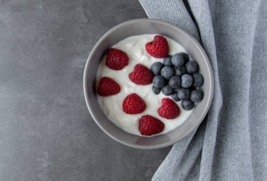 Doğal taze Yunan yoğurdu, ahududu, böğürtlen ve siyah tabakta ve peçeteyle sağlıklı kahvaltı.. 
