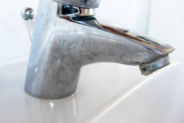 Water dripping of lime on metal tap. Durty faucet in bathroom.