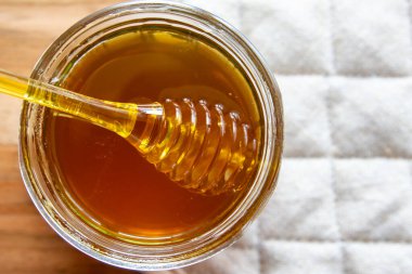 Balpeteği ve sarı kaşıkla bal kavanozu ahşap masada kal..