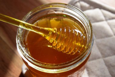 Balpeteği ve sarı kaşıkla bal kavanozu ahşap masada kal..