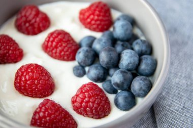 Doğal taze Yunan yoğurdu, ahududu, böğürtlen ve siyah tabakta ve peçeteyle sağlıklı kahvaltı.. 