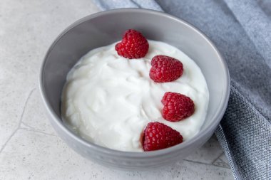 Doğal taze yoğurt, siyah tabakta ahududu ve sağlıklı kahvaltı için peçete.. 