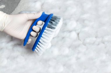 Plastik mavi fırçalı lastik eldiven ve yerde temizlik için köpük. Ev temizliği kavramı.