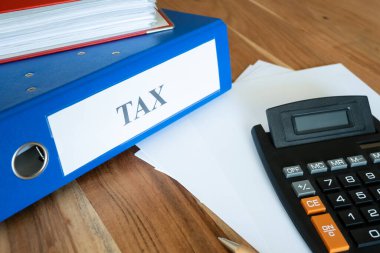 Vergi belgeleri, kalem, hesap makinesi ve kağıt içeren mavi dosya. İş için ofis işi..