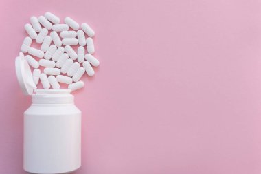 Pembe arka planda kavanozda bir sürü beyaz hap ve uyuşturucu var. Sağlık sigortası konsepti. Metin için boşluk.