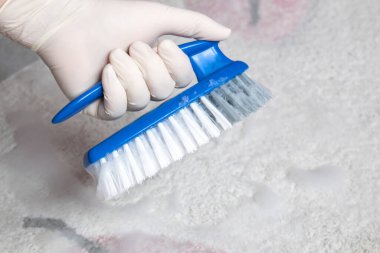 Plastik mavi fırçalı beyaz lastik eldiven ve yerleri temizlemek için köpük verin.. 