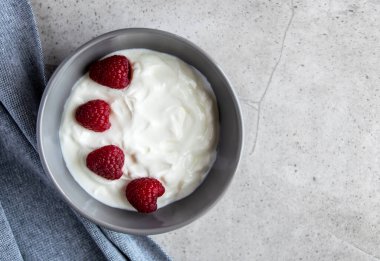 Gri tabakta ahududu böğürtlenli doğal taze Yunan yoğurdu ve sağlıklı kahvaltı için peçete. Metin için boşluk.