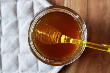 Ballı büyük cam kavanoz bal peteği ve sarı kaşık ahşap masada kırsal peçeteyle kal..