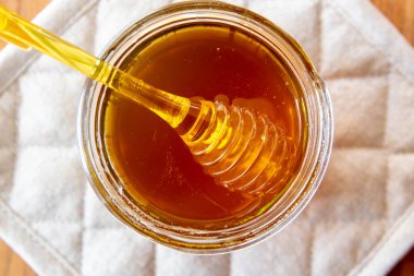 Ballı büyük cam kavanoz bal peteği ve sarı kaşık ahşap masada kırsal peçeteyle kal..