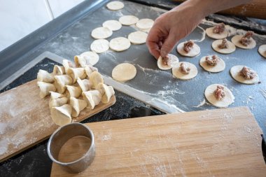 Mutfaktaki gri masada hamur köftesi hazırlayan adam. Yiyecek konsepti.