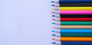 Lila kağıdının arka planında bir sürü renkli kalem var. Kapatın. Tasarım konsepti. Metin için boşluk. 