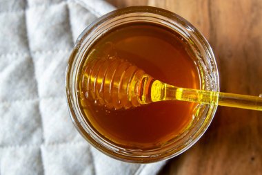 Ballı büyük cam kavanoz bal peteği ve sarı kaşık ahşap masada kırsal peçeteyle kal..