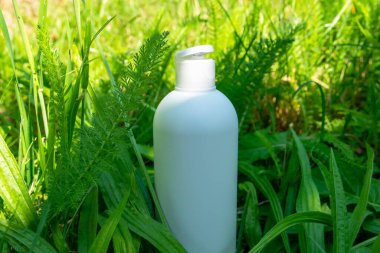 Yeşil çimlerde krema, merhem ya da yağ için beyaz plastik şişe. Kozmetik için doğa arkaplanı. 