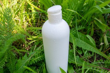 Yeşil çimlerde krema, merhem ya da yağ için beyaz plastik şişe. Kozmetik için doğa arkaplanı. 