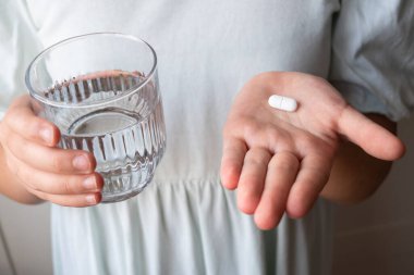 Hap ve bardak, elinde su olan bir çocuk. Eczaneden sağlık hizmeti. Çocuk hastalık yüzünden evde oturuyor..