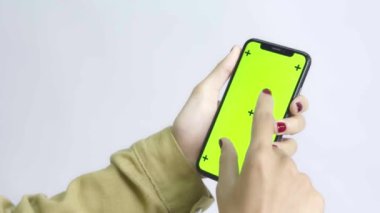 Yeşil Ekran Chroma Anahtarı Tanınmayan zeytin tenli Asyalı kadın beyaz arka planda cep telefonunu kullanıyor. Parmağınla ekranı büyüt